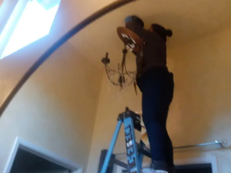 Electrician installing a chandelier in a Dexter residence